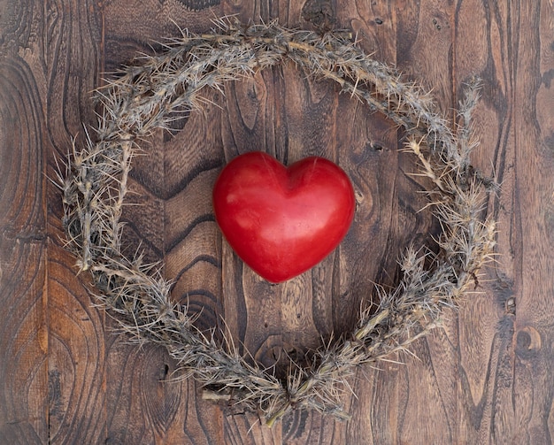 Photo heart shaped wreath with a crown of thorns on a wooden background