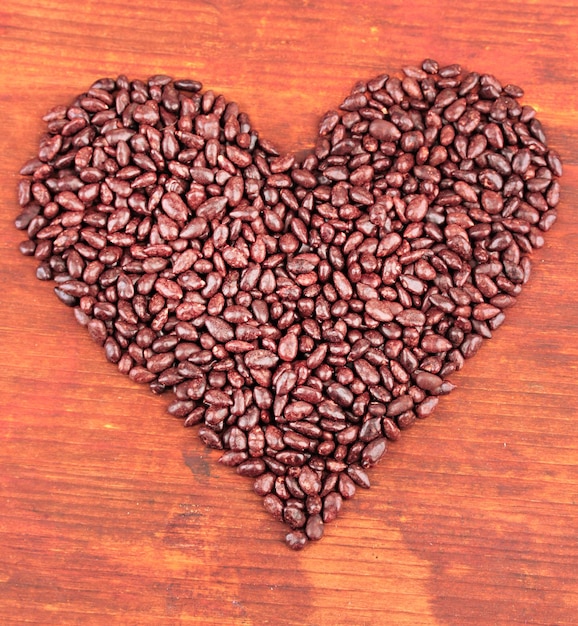 Photo heart of sunflower grains in chocolate on brown wooden background