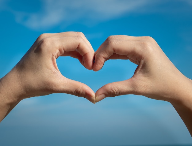 Simbolo del cuore dalle mani sul cielo blu. concetto di amore o salute.