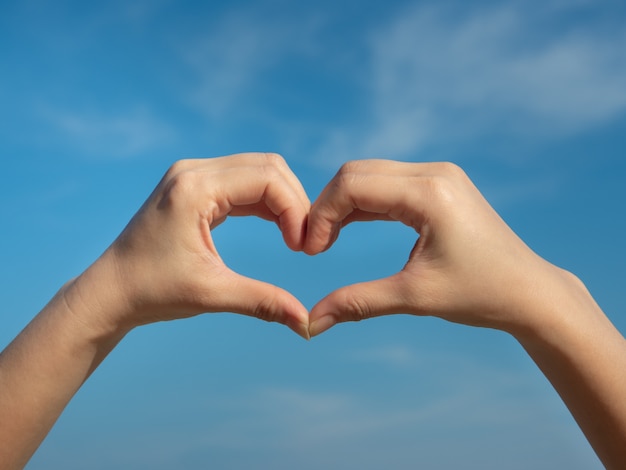 Heart symbol from hands on the blue sky.