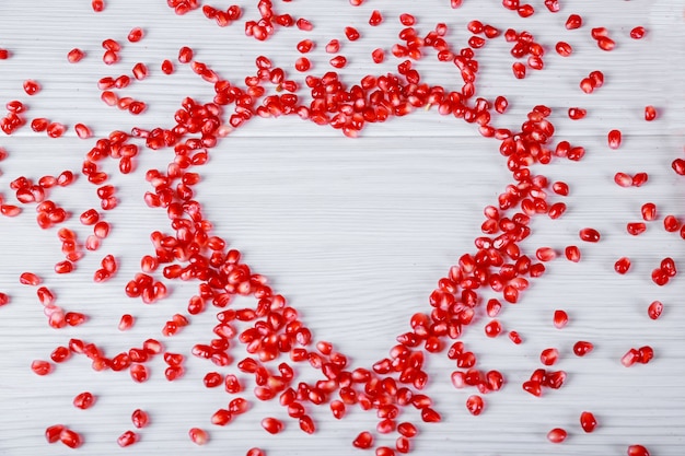 Heart symbol made from pomegranate seeds on white background