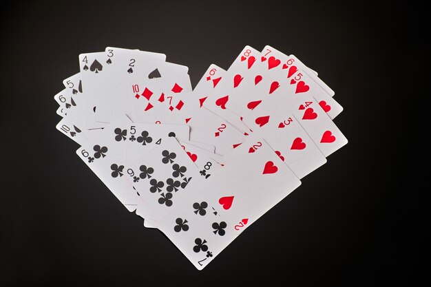 Heart symbol made of playing cards dark reflective background