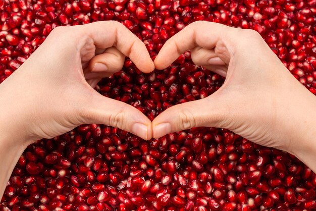 Heart symbol Pomegranate seeds in woman hand