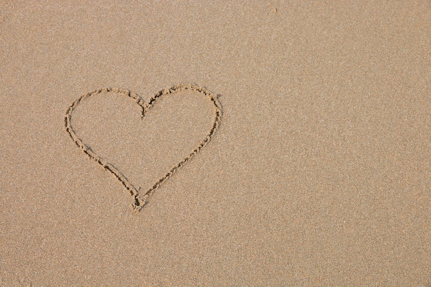 모래 해변에서 심장 기호입니다.