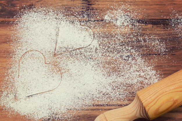 Heart of white flour on a brown wood