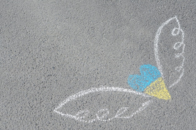 Heart and wings drawn with blue and yellow chalks on asphalt outdoors Space for text