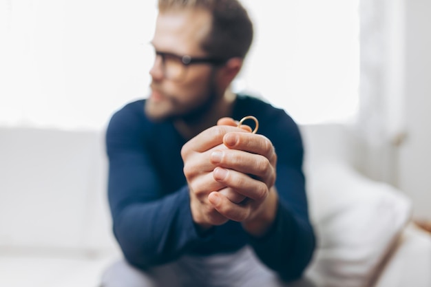 Heartbroken man holding a wedding ring