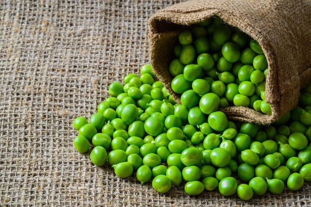 Hearthy fresh green peas and pods on rustic wood table.