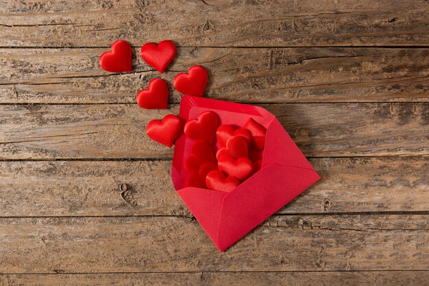 Hearts coming out of an red envelope on wooden table