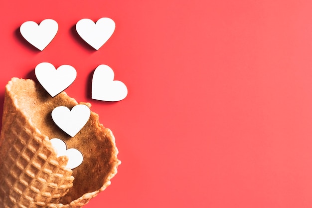 Photo hearts in an empty ice cream cone on a red bacground.