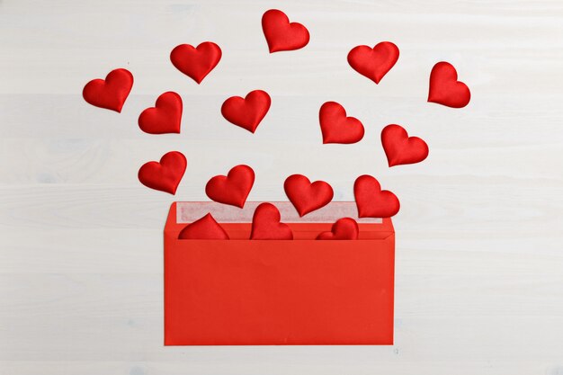 Photo hearts flying out of a red paper envelope