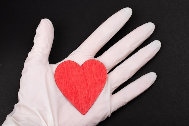 Hearts in hand with rubber gloves isolated on black