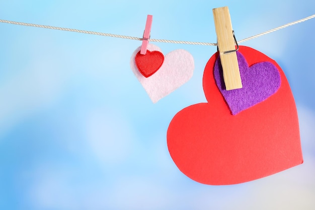 Hearts hanging on rope on bright background