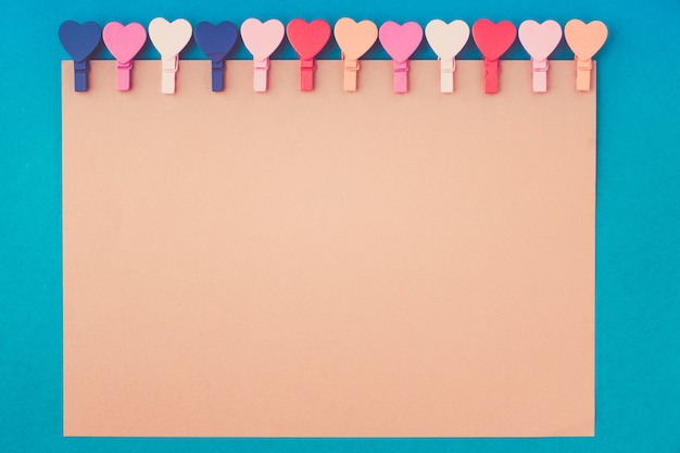 Hearts hold a note paper on a blue background