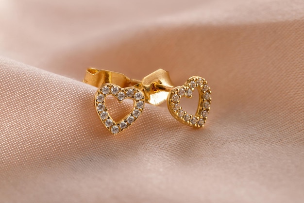 Hearts shape gold stud earrings with diamonds on pink background Romantic jewelry Soncept for Valentine's Day