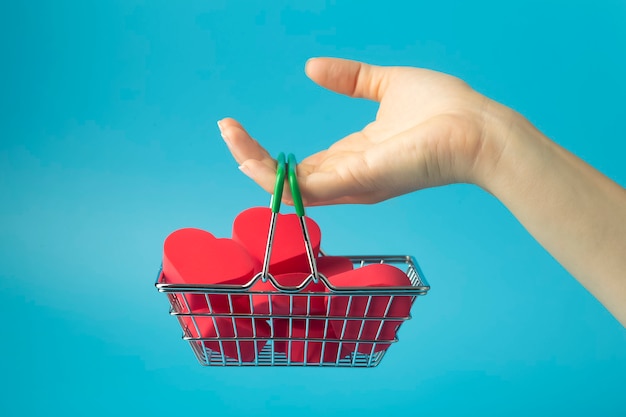 Hearts in shopping cart ona a colored background. Background for Valentine's Day (February 14) and love.