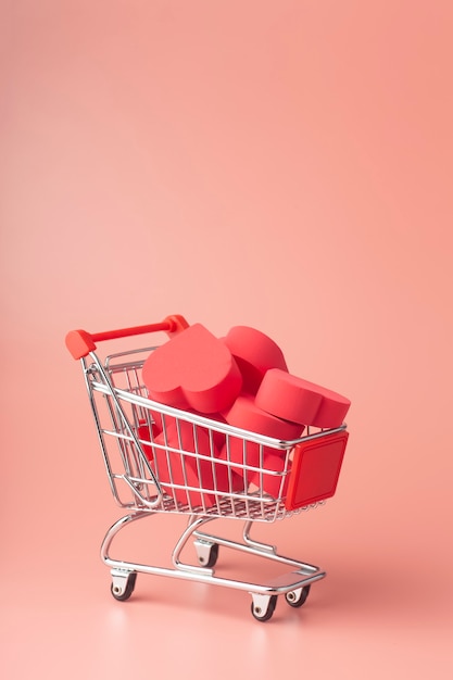 Hearts in shopping cart and supermarket trolley against colored background. Background for Valentine's Day (February 14) and love.