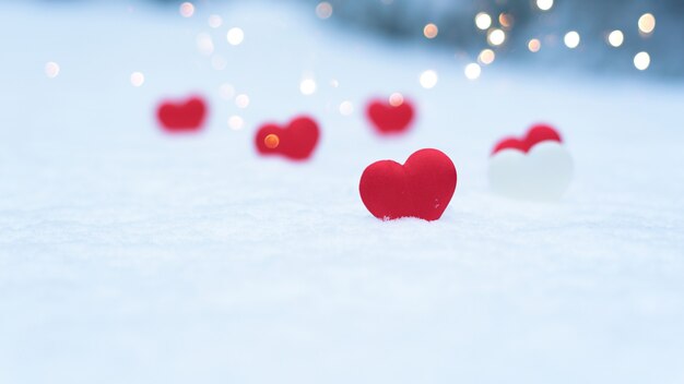 Hearts on snow with blurred light garlands