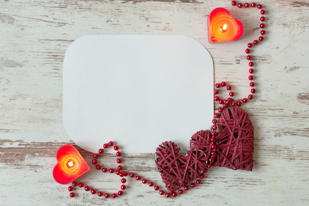 Hearts with red bead chain and candles on wooden table. St. Valentines Day blank greeting card