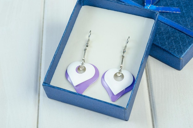 Heartshaped earrings fashion jewelry in Very Peri 2022 color on a white wooden background closeup