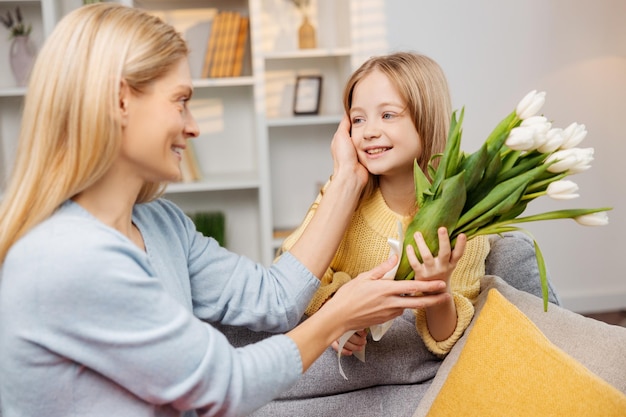 Heartwarming scene on Mothers Day Daughter presents a white bouquet to her overjoyed mother