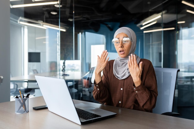 Heat and heat in the office business woman in hijab waving her hands trying to refresh and cool down