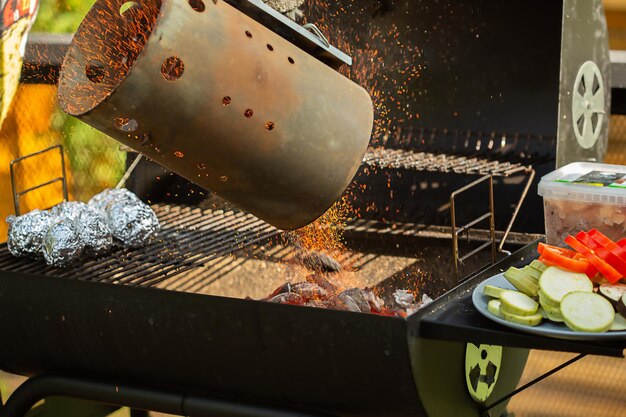 I carboni accesi vengono versati nel braciere per la cottura di spiedini e verdure al forno