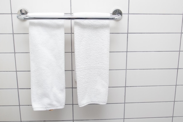 Photo heated towel rail on bathroom wall. white towels drying on a heated towel rail.