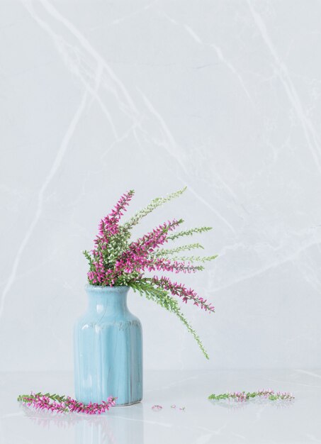 Heather   bouquet in blue vase on gray marble background