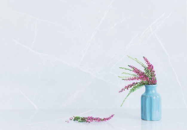 heather bouquet in blue vase on gray marble background