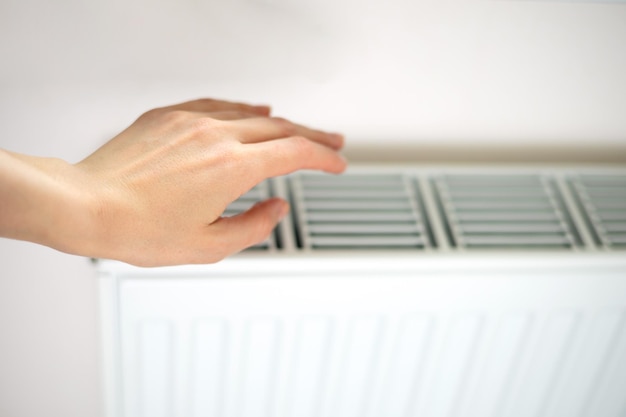 Heating radiator A woman warms her hands at the battery heating season Energy