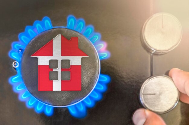 Heating season or gas use in Denmark Concept model of a house stands near the flame of a gas boiler on a black background The cost of using natural gas in Denmark