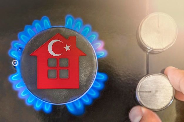 Stagione di riscaldamento o utilizzo del gas in turchia il modello concettuale di una casa si trova vicino alla fiamma di una caldaia a gas su sfondo nero il costo dell'utilizzo del gas naturale in turchia