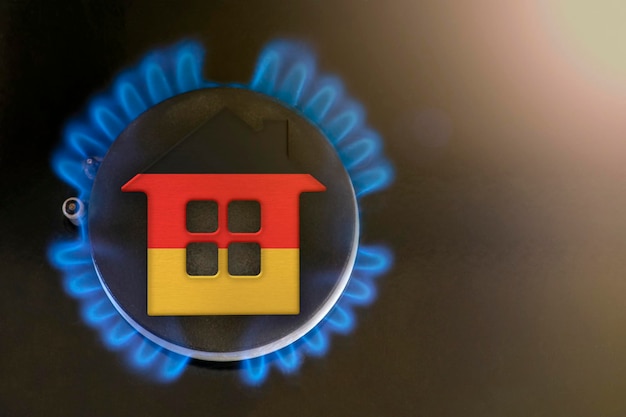 Heating season Germany The beginning of the heating season on natural gas Concept model of a house stands near the flame of a gas boiler on a black background Germany home heating cost