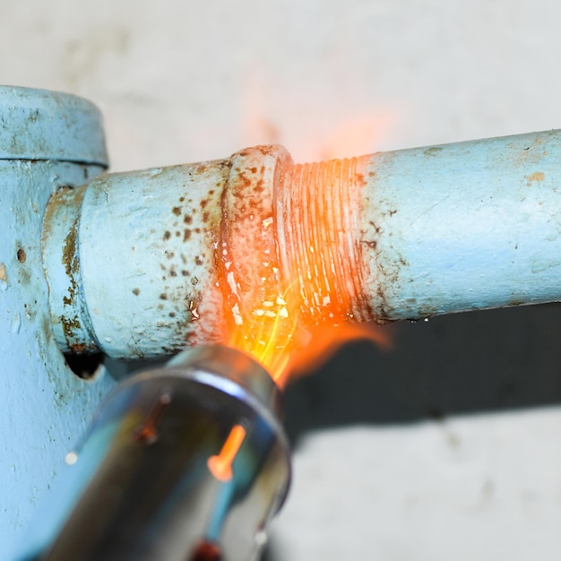 Foto riscaldare un tubo d'acciaio con una torcia la fiamma di una torcia