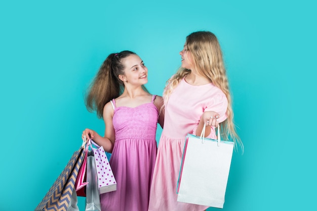 Heavy bags teen girls hold paper bag buy gifts for holiday shopaholic kids with purchase packages cheerful children go shopping black friday concept kids on cyber monday big sale