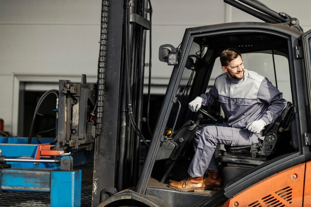 A heavy industry laborer is driving forklift outside