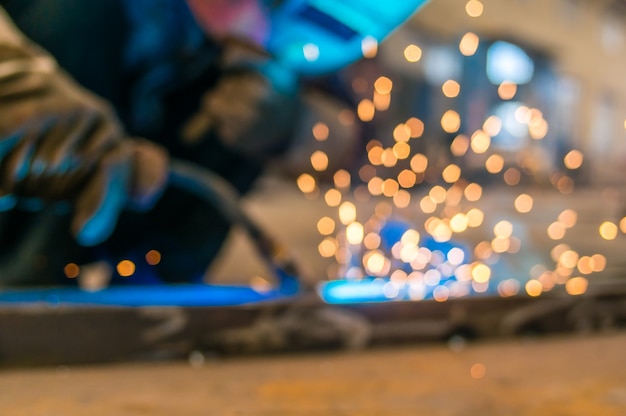 Heavy industry welder worker in protective mask hand holding arc welding torch working on metal construction