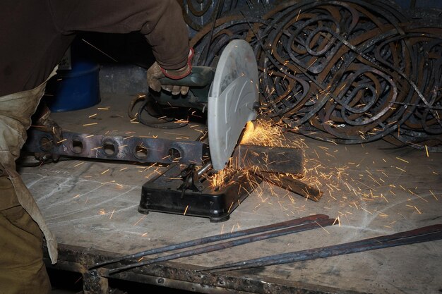 Heavy industry worker cutting steel with angle grinder