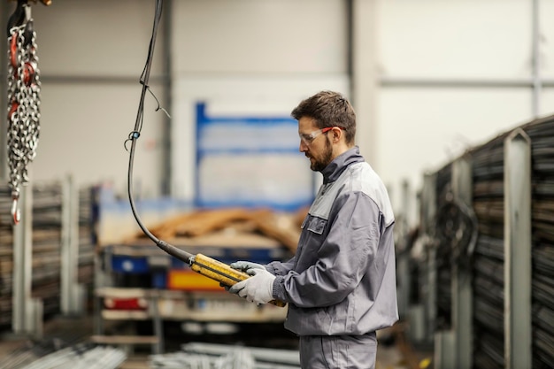 A heavy industry worker is managing crane in facility