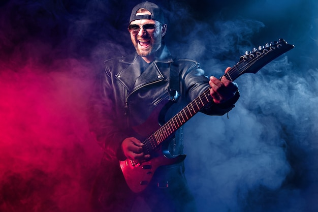 Heavy metal musician is playing electrical guitar. Shot in a studio.