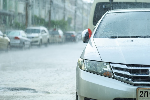 Сильный дождь падает на стоянку автомобилей перед домом в дождливый день.