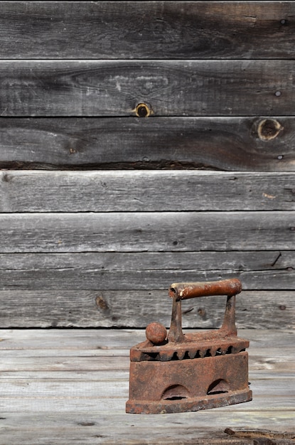 The heavy and rusty old coal iron lies on a wooden surface