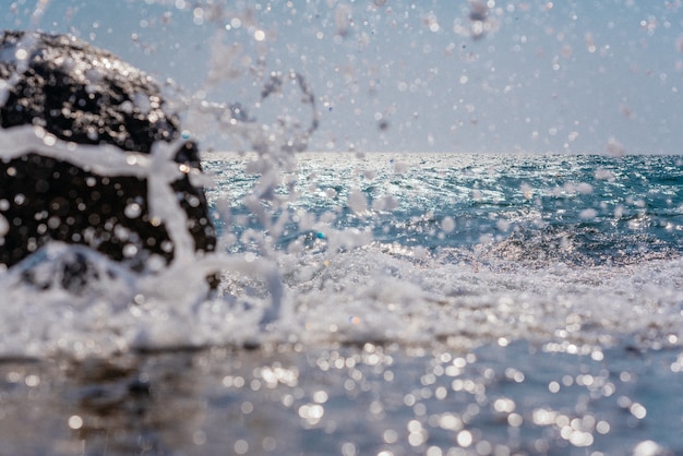 A heavy sea wave breaks into white foam splashes on the shore