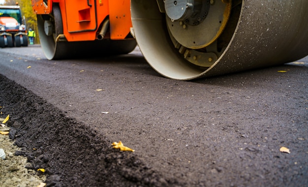 Heavy vibration roller at asphalt pavement works. Road repairing. Selective focus, cropped photo. New asphalt.