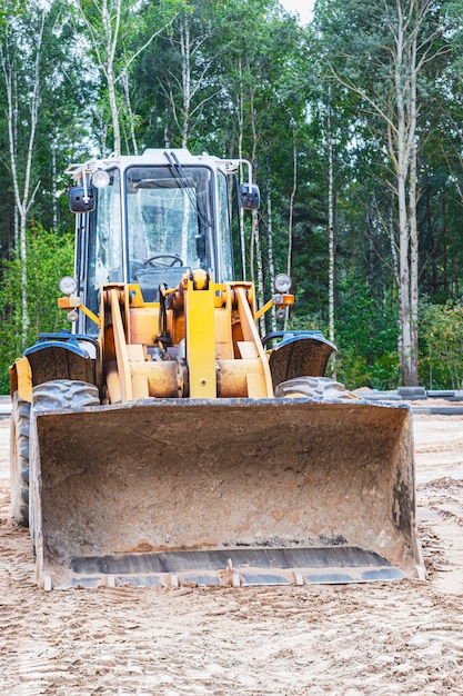 Pala gommata pesante con un secchio in un cantiere edile. attrezzature per lavori in terra, trasporto e carico di materiali sfusi: terra, sabbia, pietrisco.