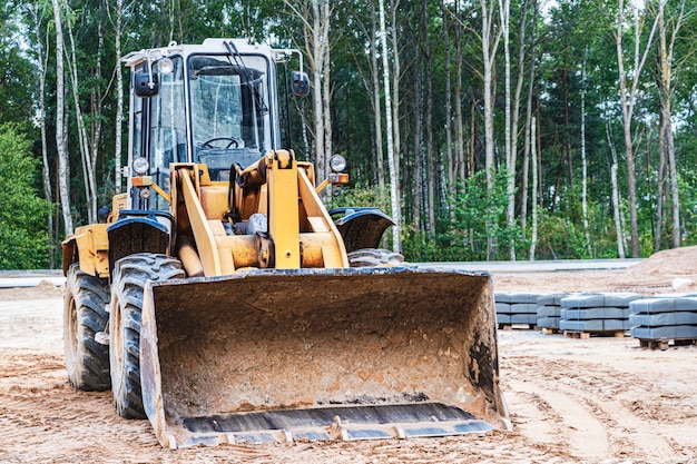 Heavy wheel loader with a bucket at a construction site. Equipment for earthworks, transportation and loading of bulk materials - earth, sand, crushed stone.