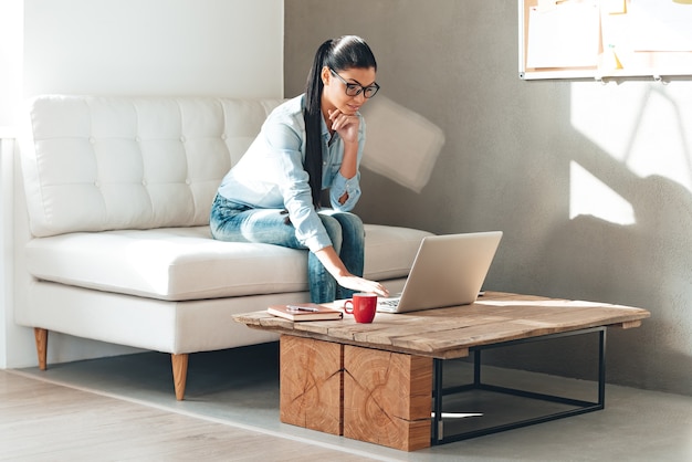 Heb wat werk te doen. Mooie jonge vrouw in glazen die aan laptop werken