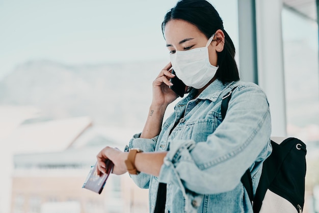 Hebben we bijna geen tijd meer om ons leven te leiden Shot van een jonge vrouw die een masker draagt met een smartphone en de tijd controleert op een luchthaven