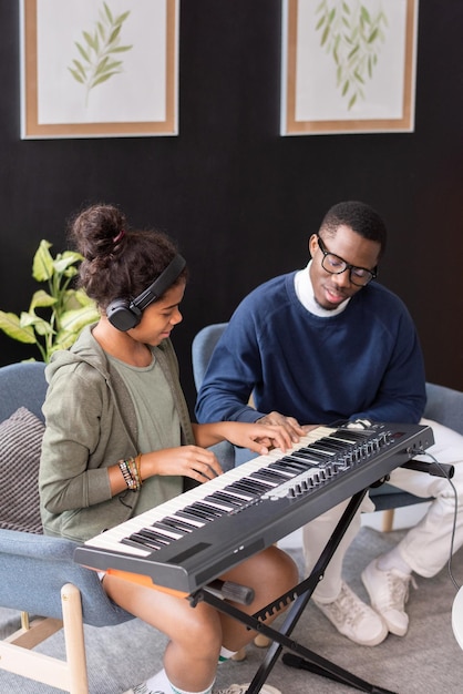 Hedendaags schoolmeisje en haar muziekleraar die muziektoetsenbord spelen